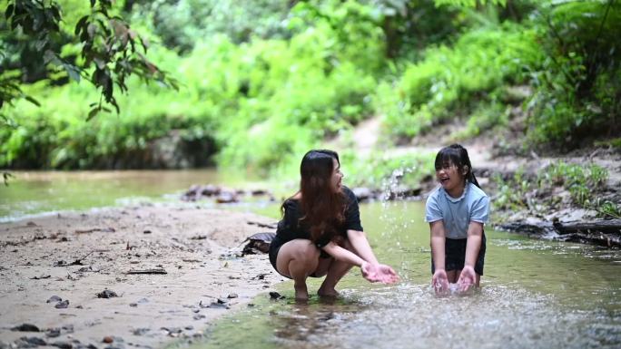 母亲与女儿在河边玩泼水游戏