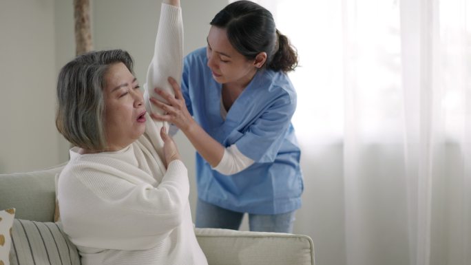 卫生工作者协助老年妇女在家锻炼