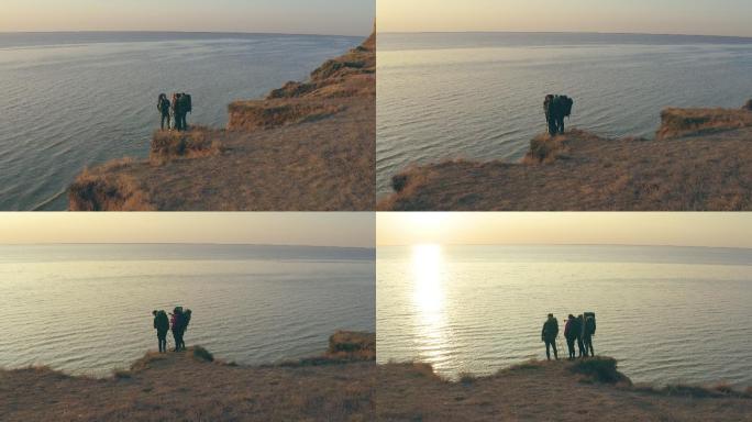 背着背包的旅行者们站在海边的沙石顶上