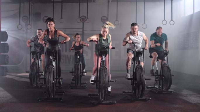 一群运动员在健身房里骑着固定自行车锻炼。