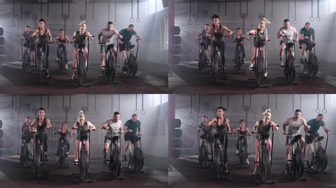 一群运动员在健身房里骑着固定自行车锻炼。