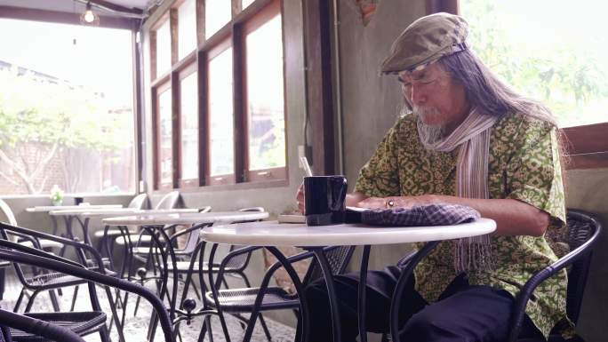 坐在咖啡馆用钢笔画画的老人