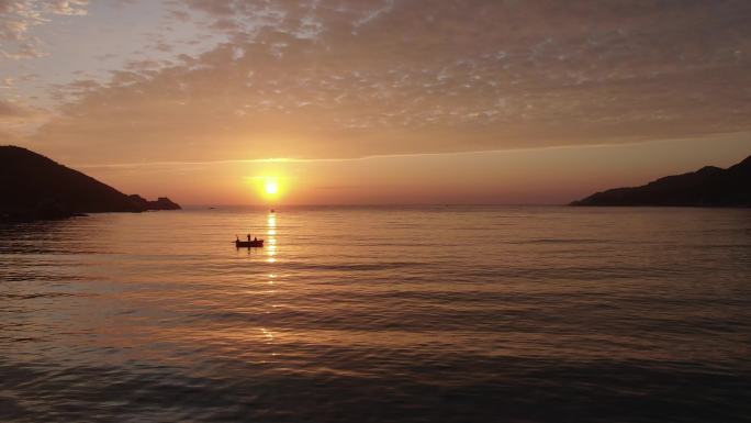 日出下后海海上的辛劳的渔民