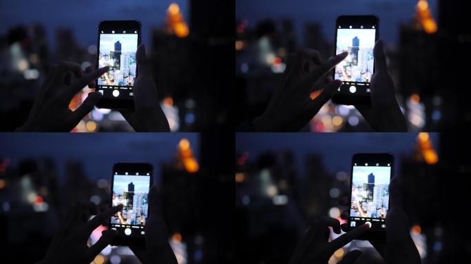 游客晚上用智能手机拍照。