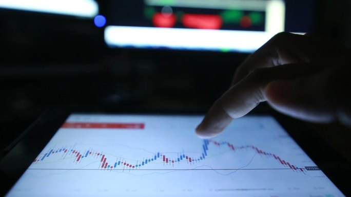 交易员在平板电脑屏幕上移动图形货币报价。