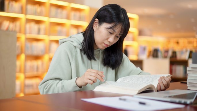 年轻女子在图书馆翻书查找资料