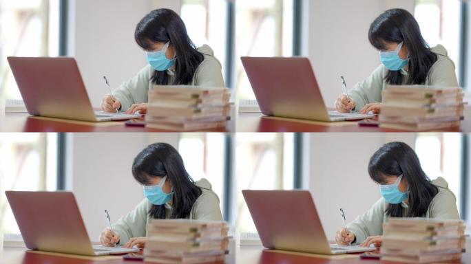 戴口罩年轻女子在图书馆用笔记本学习