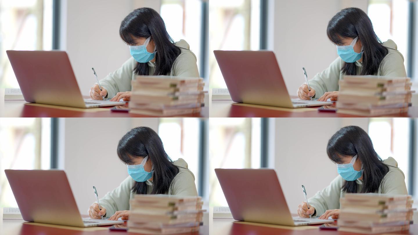 戴口罩年轻女子在图书馆用笔记本学习