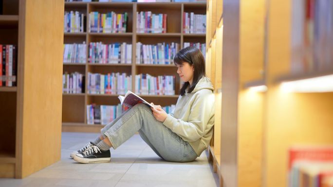 年轻女子图书馆坐在书架前翻看书本