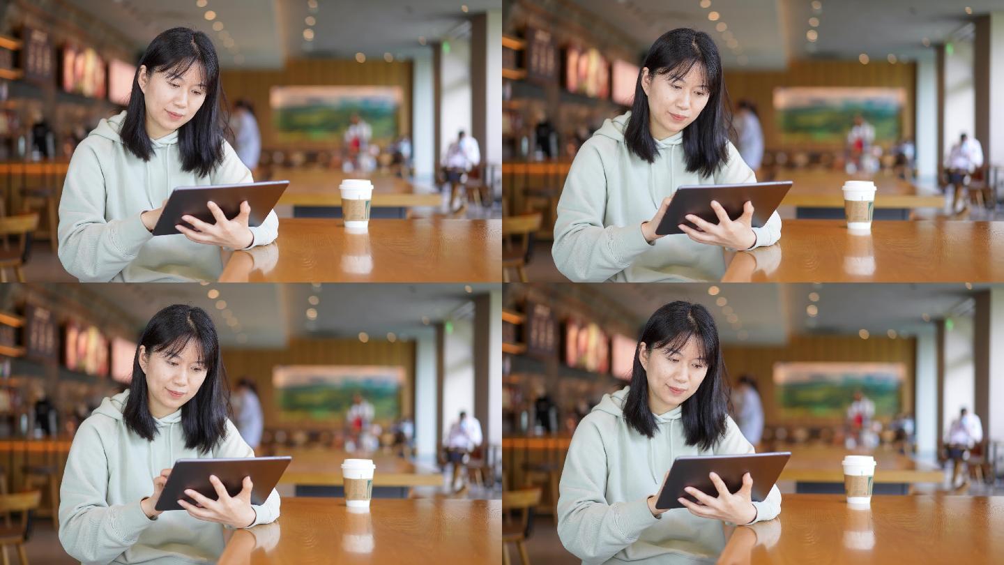 年轻女子在咖啡店使用平板电脑看视频