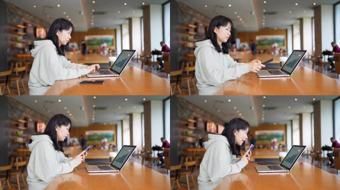 年轻女子在咖啡店使用手机和笔记本电脑工作