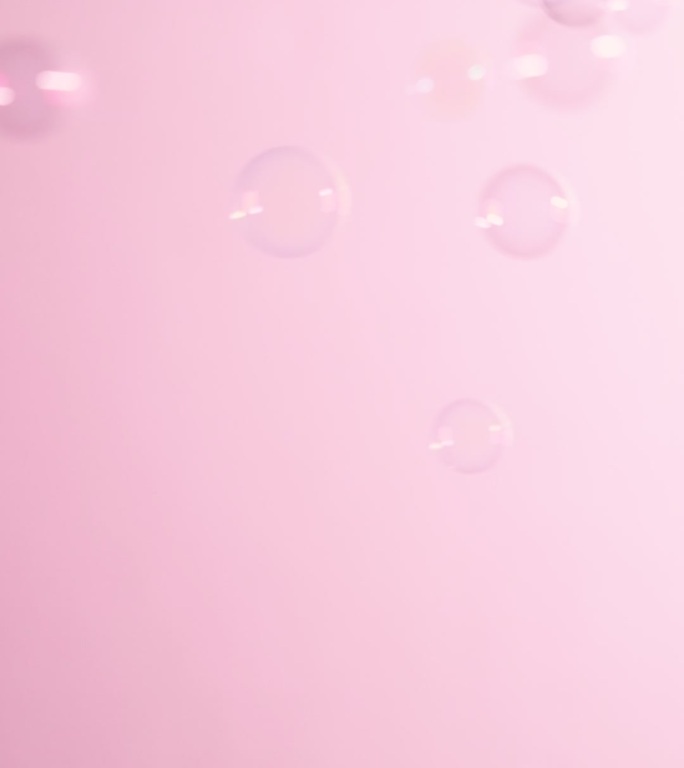 肥皂泡在粉红色的背景上飞过。