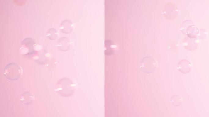 肥皂泡在粉红色的背景上飞过。