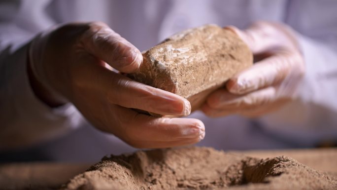 考古发掘人员手捧文物翻来覆去观察研究