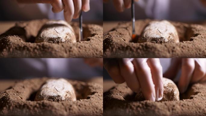 考古发掘人员用刷子轻轻扫去文物上沙泥拿走