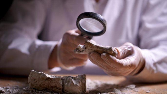 考古人员手捧文物用放大镜观察研究