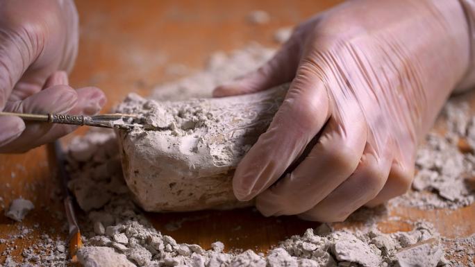 考古人员用洛阳铲铲除文物上的灰土