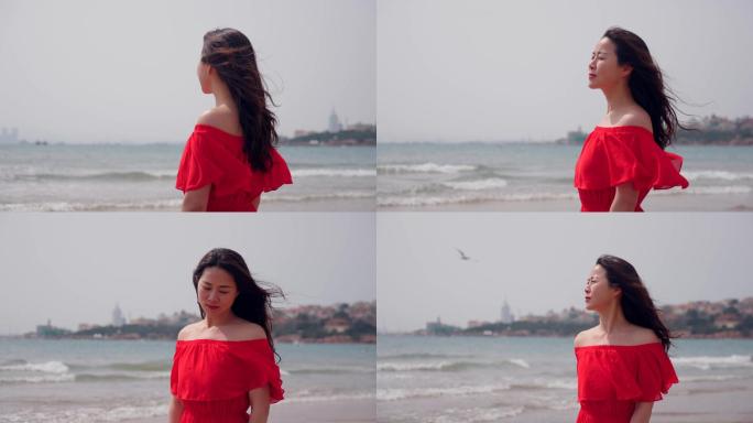 海边红衣美女旅游度假感受海风