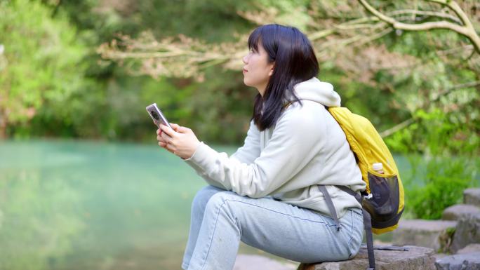 春天年轻女孩在池塘边玩手机刷手机刷朋友圈