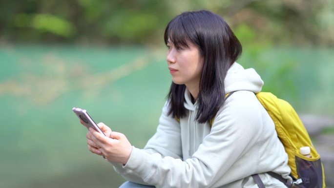 春天年轻女孩在池塘边玩手机刷手机刷朋友圈