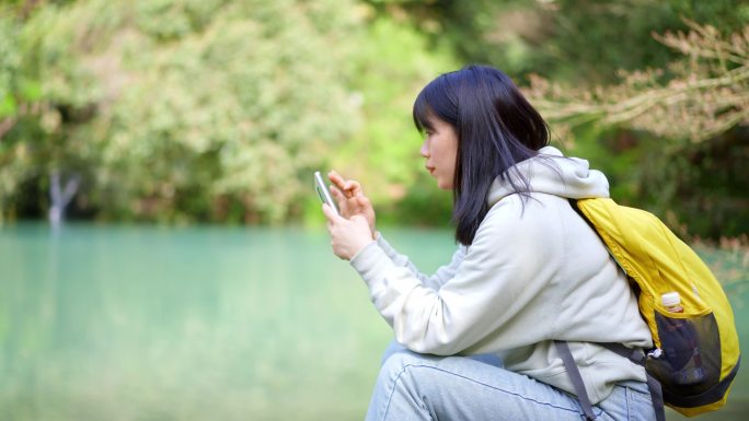 春天年轻女孩在池塘边玩手机刷手机刷朋友圈