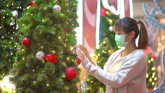 女性戴着防护口罩装饰商场的圣诞树