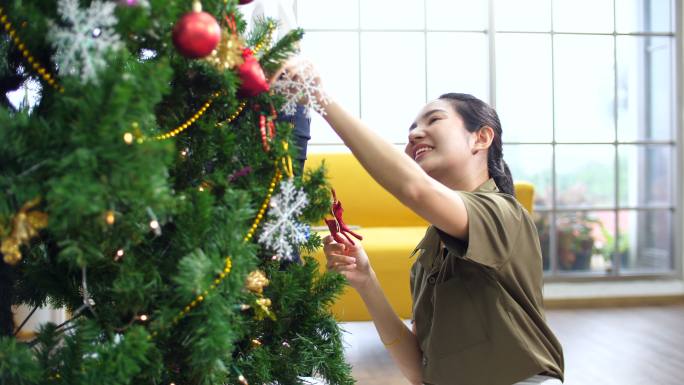 女孩在装饰圣诞树笑脸开心装点圣诞树