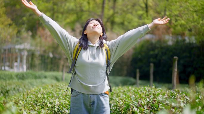 春天年轻女孩在茶园里驻足抬头闭目张开双臂