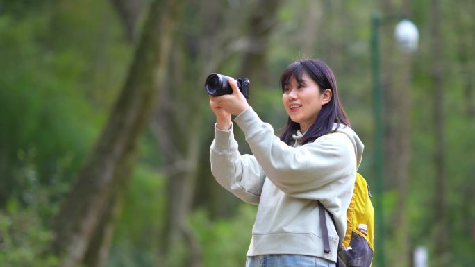 春天年轻女孩郊游公园拿相机拍摄美丽景色