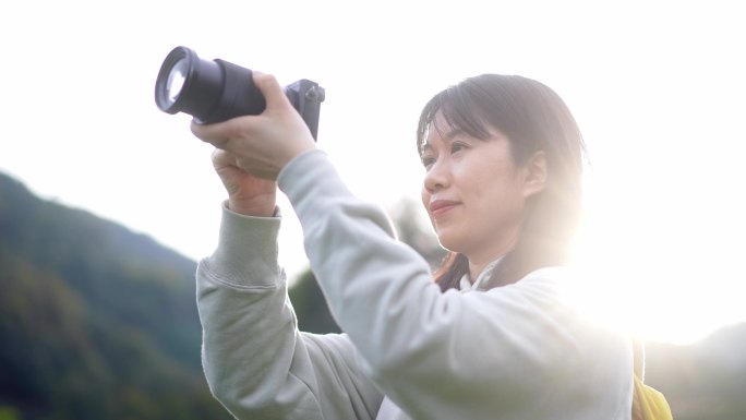 春天年轻女孩郊游公园拿相机拍摄美丽景色