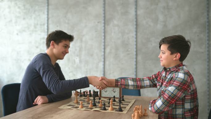 两个男孩下棋后握手