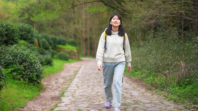 春天年轻女孩郊游公园小路上边走路边看风景