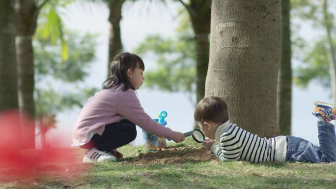 小孩玩放大镜观察泥土