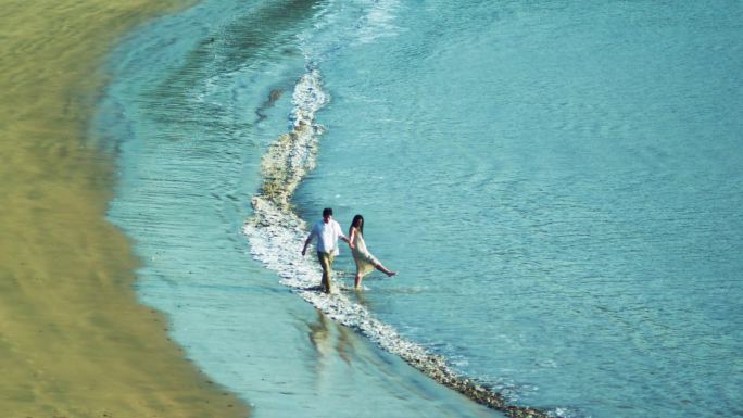 情侣手牵手在沙滩上散步
