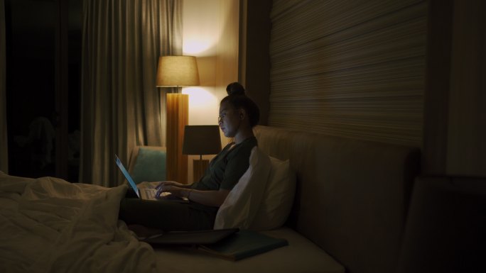 年轻女子在深夜使用笔记本电脑。
