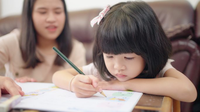在线学习的小女孩妈妈母亲指导辅导写作业教