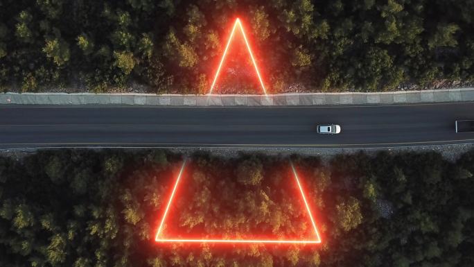 三角形霓虹灯穿过沥青路、森林路中间