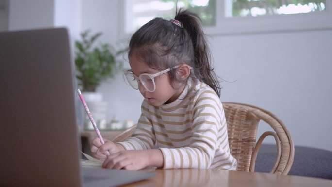 可爱的小女孩戴着眼镜在家学习