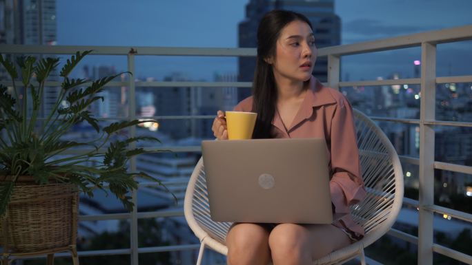夜间工作的妇女单身美女茶杯喝茶阳台上网