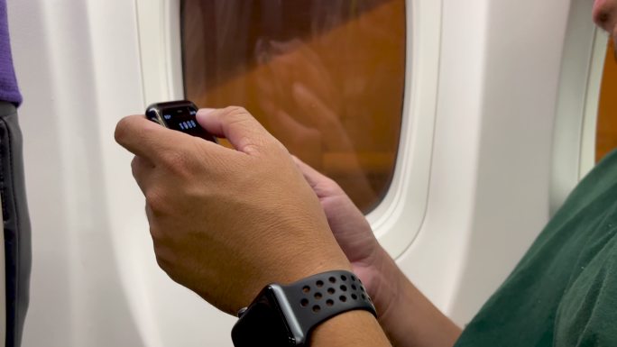 亚裔男子在飞机上使用智能手机