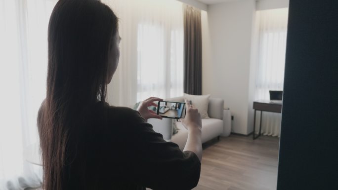 女子手持手机在室内拍照