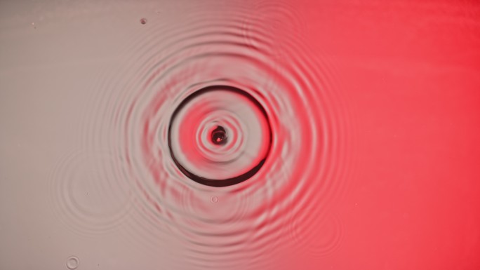 当水滴撞击银色和红色表面产生同心涟漪