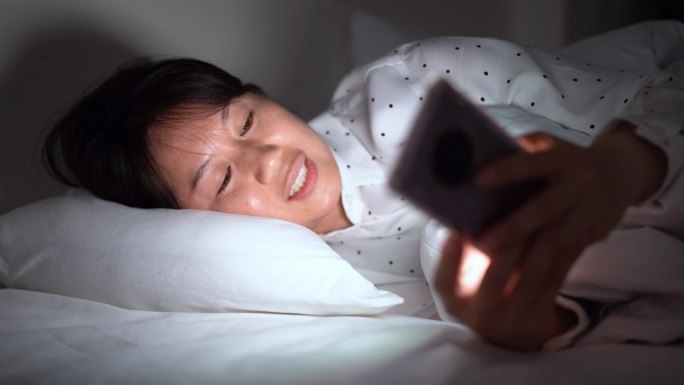 周末年轻女孩躺床上玩手机刷手机刷朋友圈