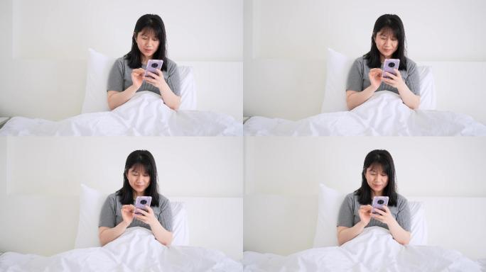 周末早晨年轻女孩坐在床上玩手机刷朋友圈