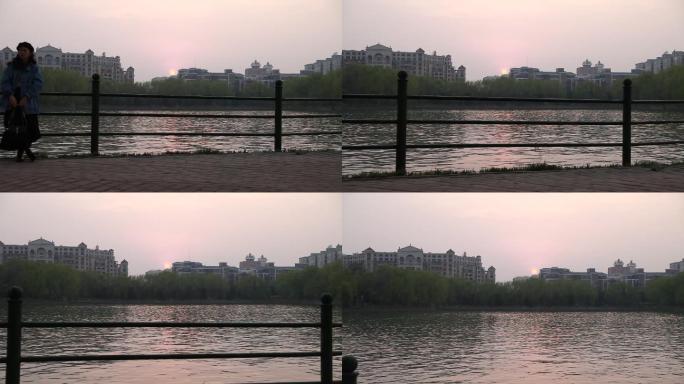 傍晚的公园湖边有一个女生在湖边拍照