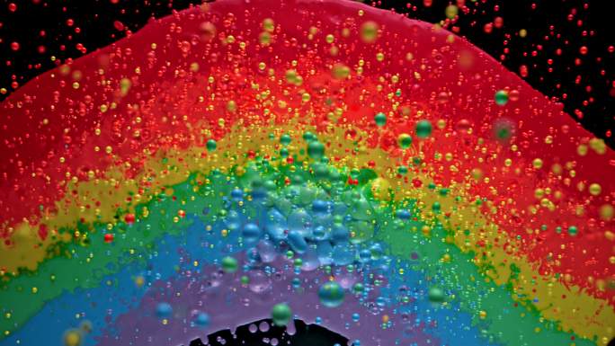 从彩虹般的色斑中飞向空中的彩色水滴的混合