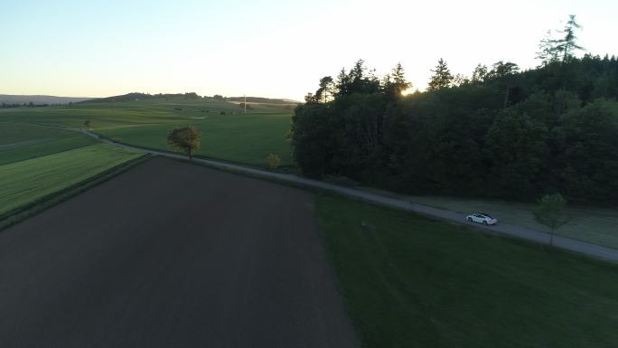 一辆白色跑车在日落时穿过乡村道路