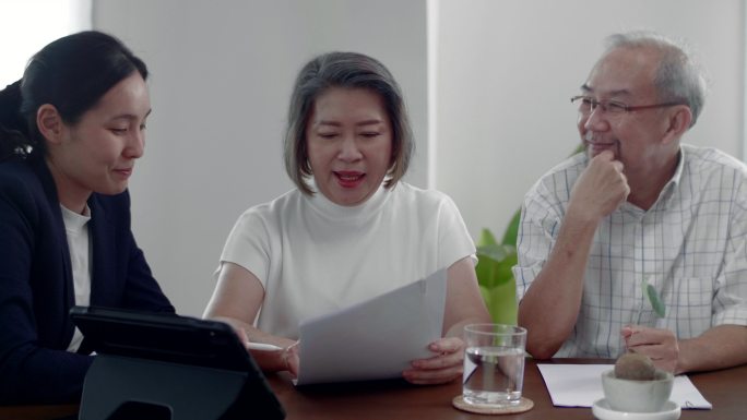 财务顾问在家向老年夫妇介绍保险计划