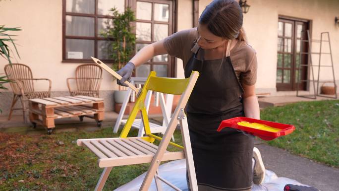 年轻女性在后院粉刷椅子