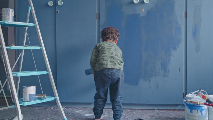 可爱的小男孩在家里粉刷墙壁